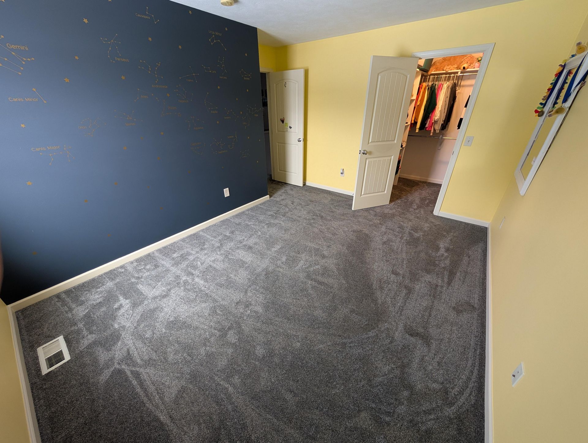 A bedroom with a walk in closet and a blue wall.