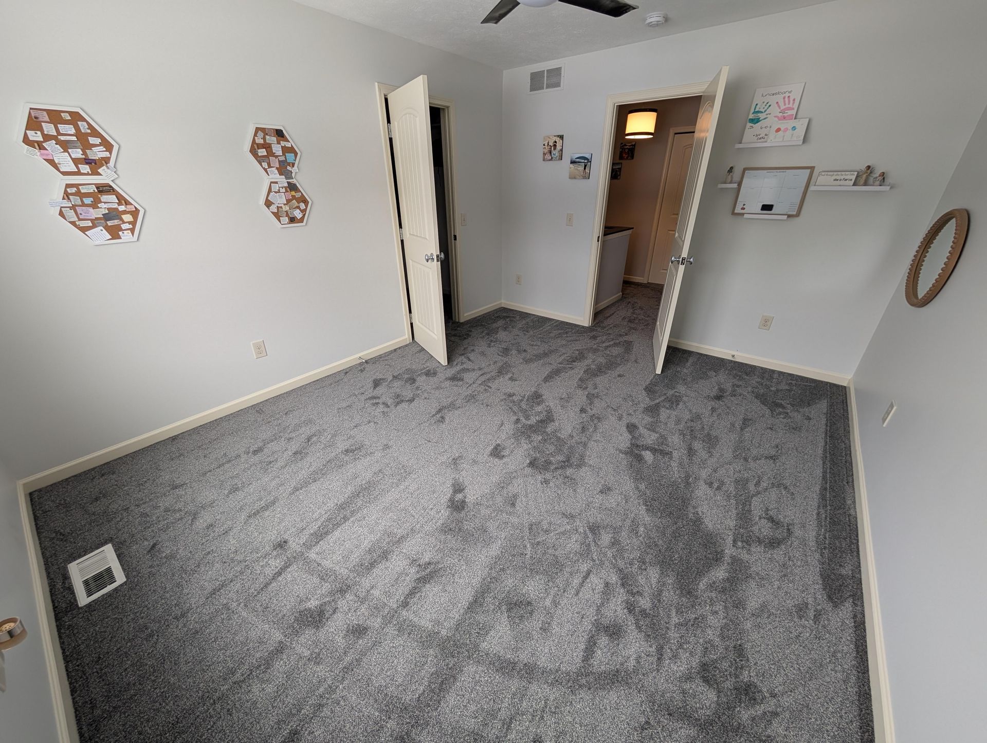 An empty bedroom with a gray carpet and a ceiling fan.