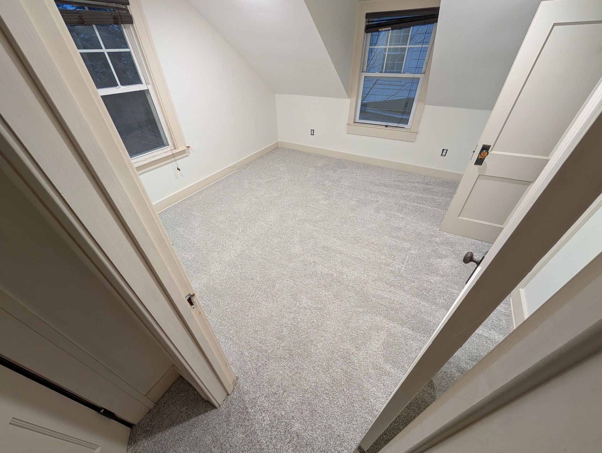 An empty room with a gray carpet and white walls