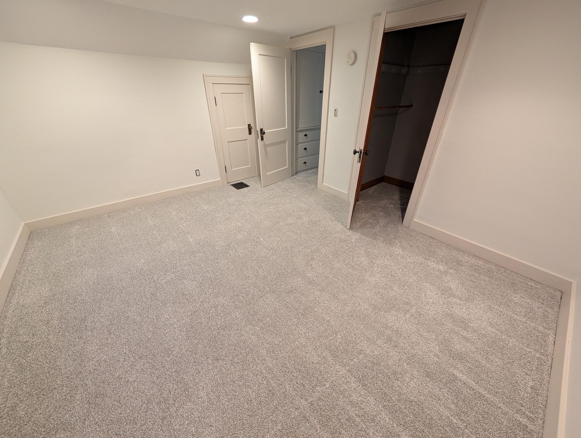 An empty room with a carpeted floor and white walls.