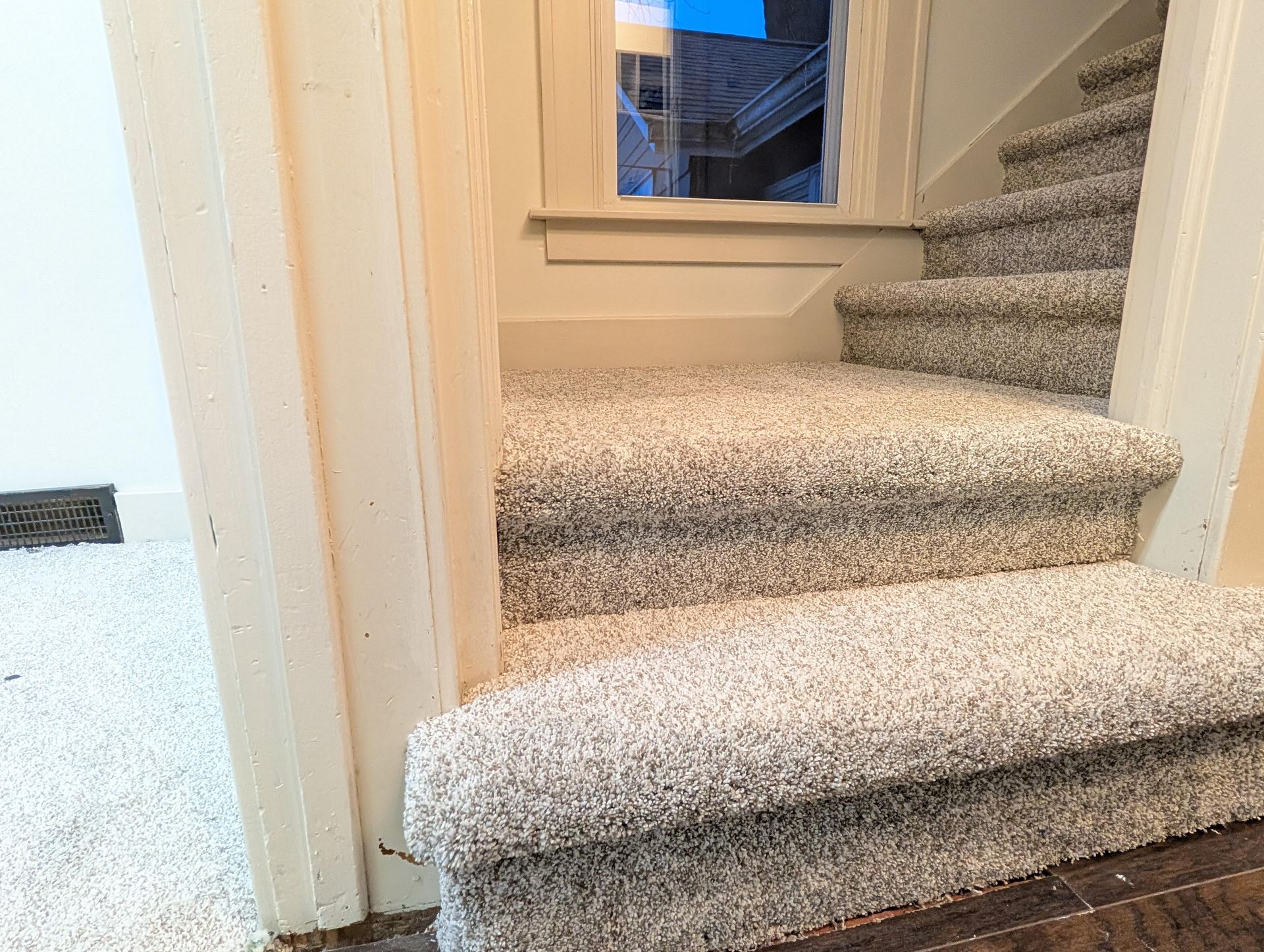 A staircase with a carpeted staircase and a window in the background.