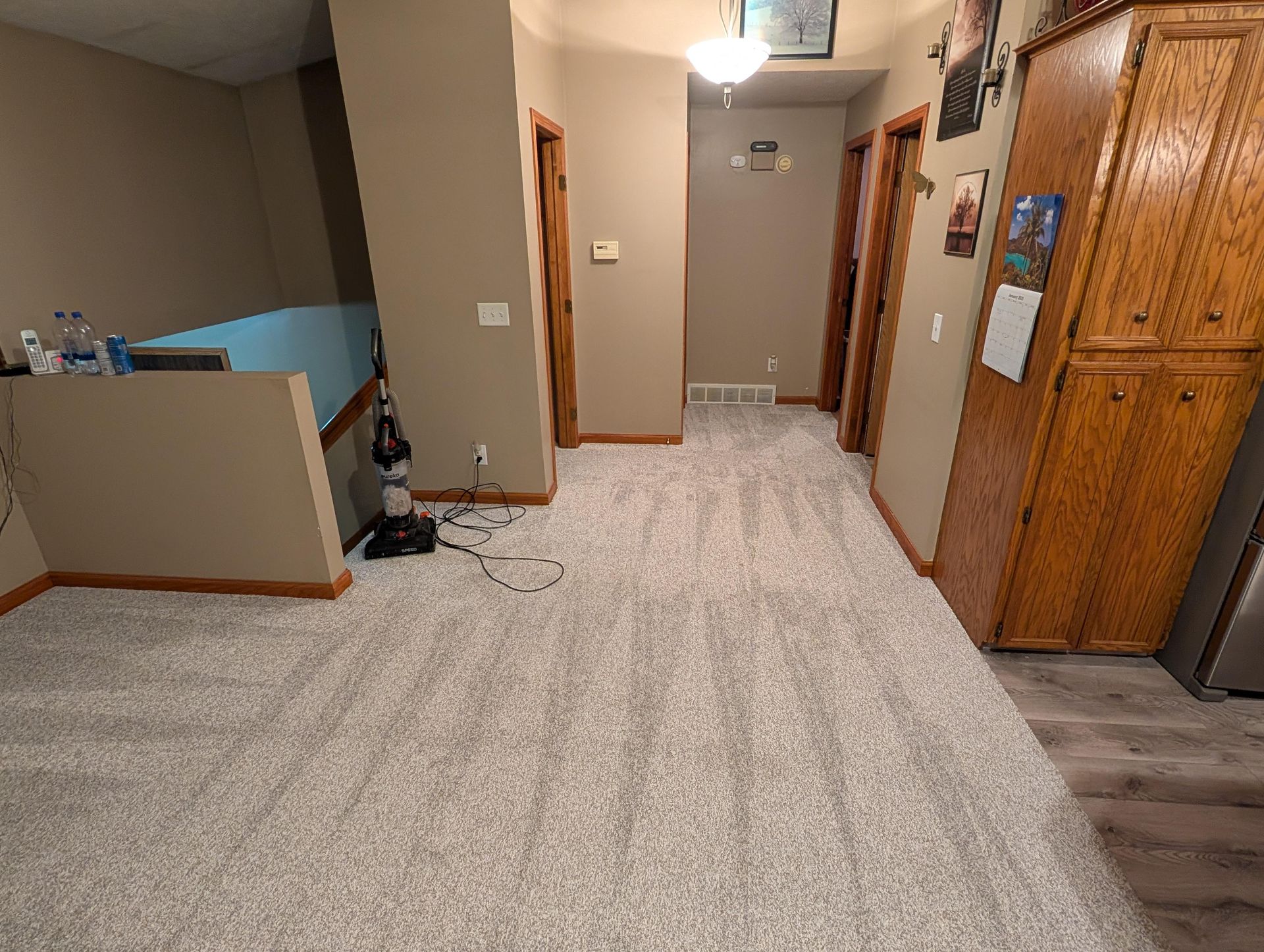 A hallway in a house with a vacuum cleaner on the floor.