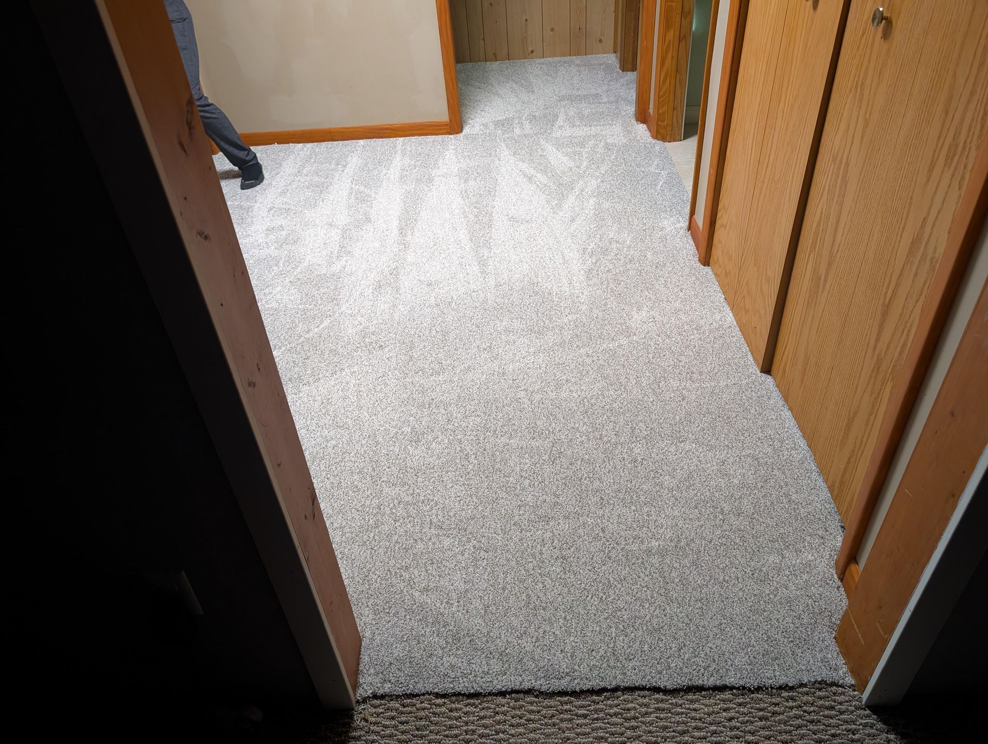 A person is standing in a hallway with a carpeted floor.