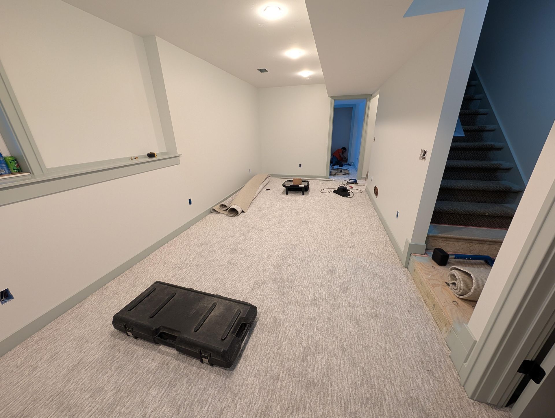 An empty basement with carpet and a toolbox on the floor.