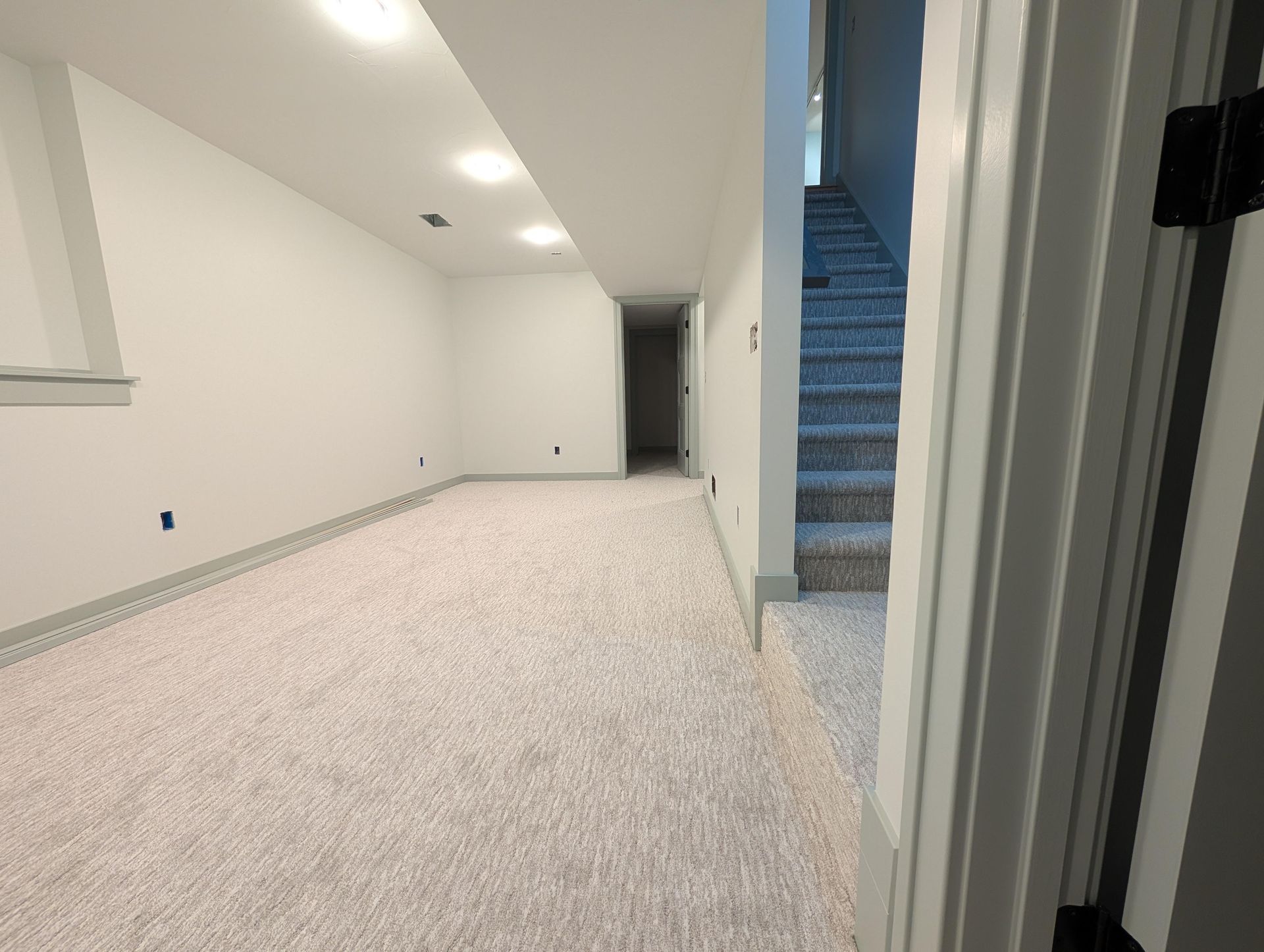 An empty basement with stairs leading up to the second floor.