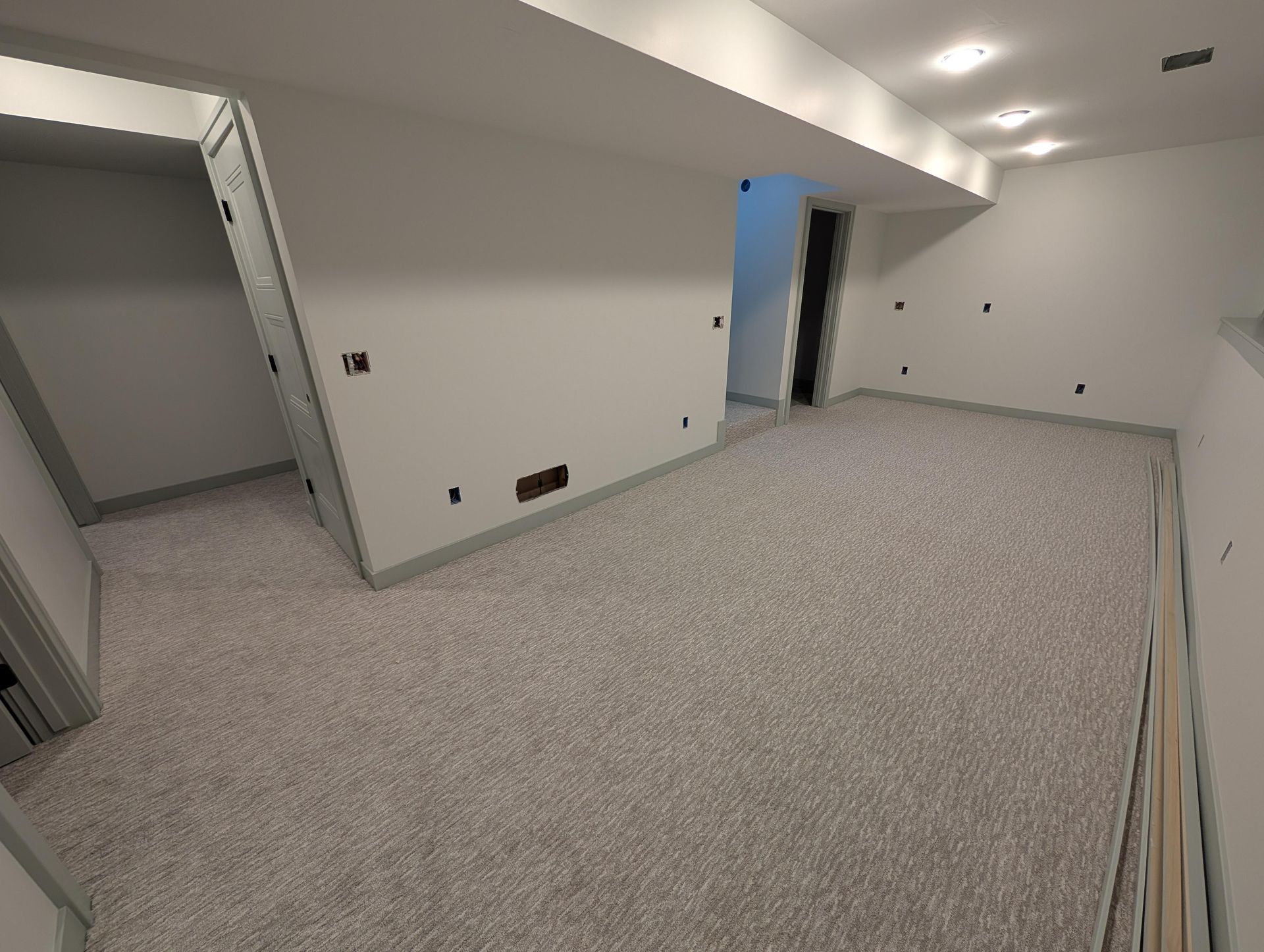 An empty basement with a carpeted floor and white walls.