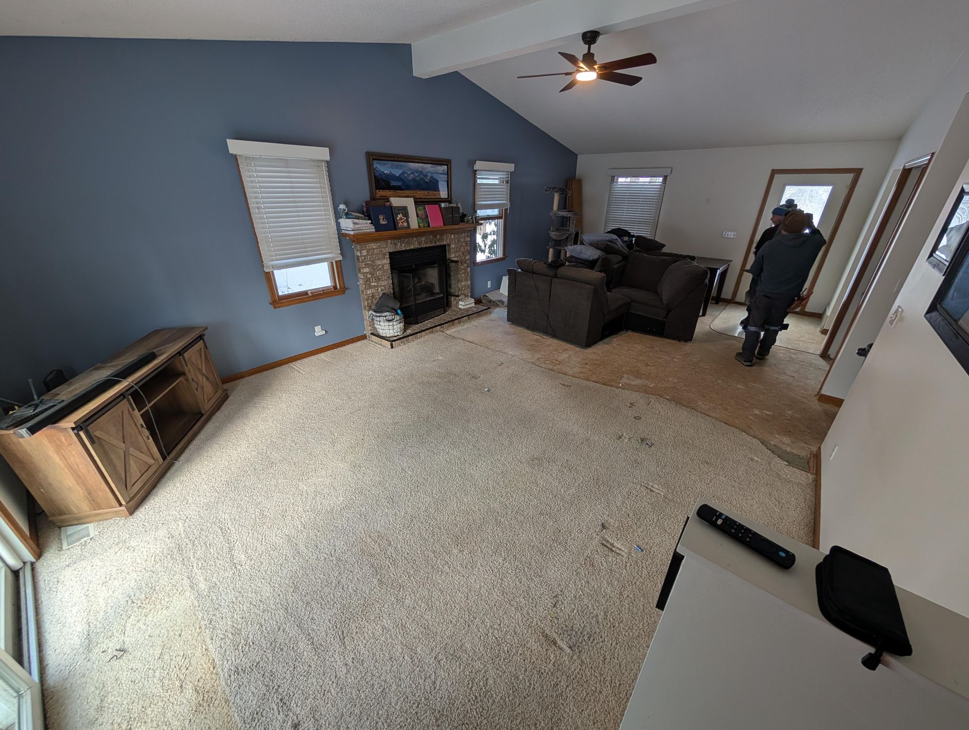 A living room with a fireplace and a ceiling fan.