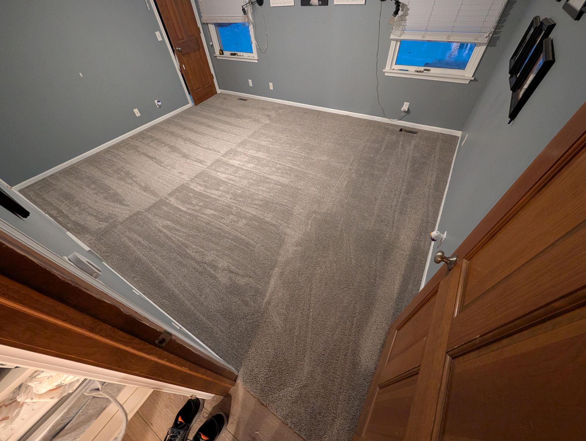 A bedroom with a carpeted floor and two windows