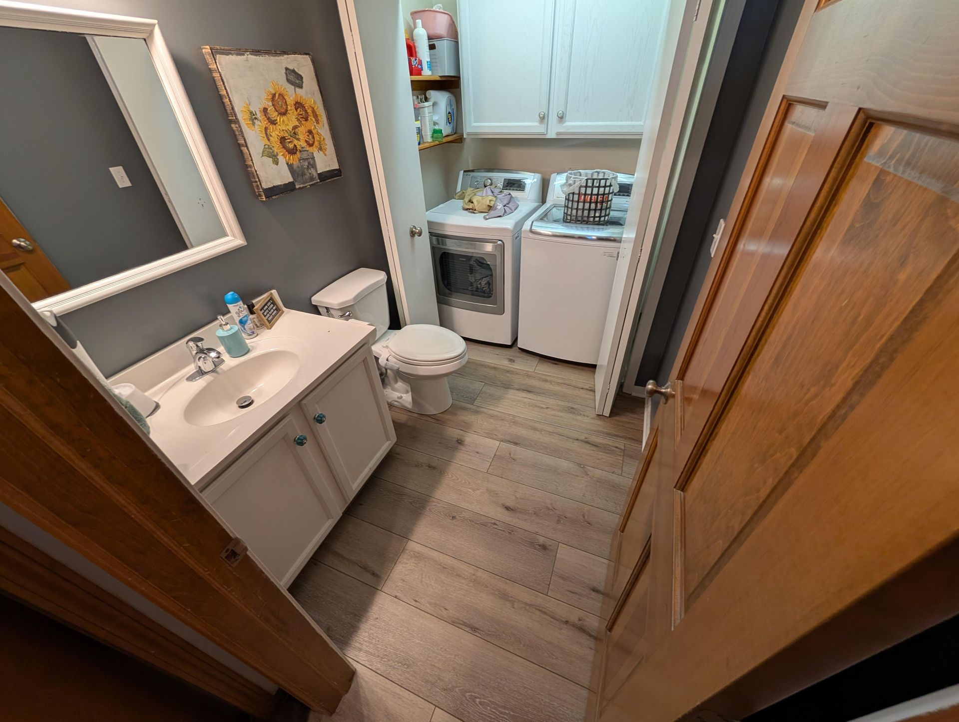 A bathroom with a sink , toilet , washer and dryer.