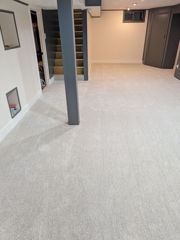 A basement with a carpeted floor and stairs.