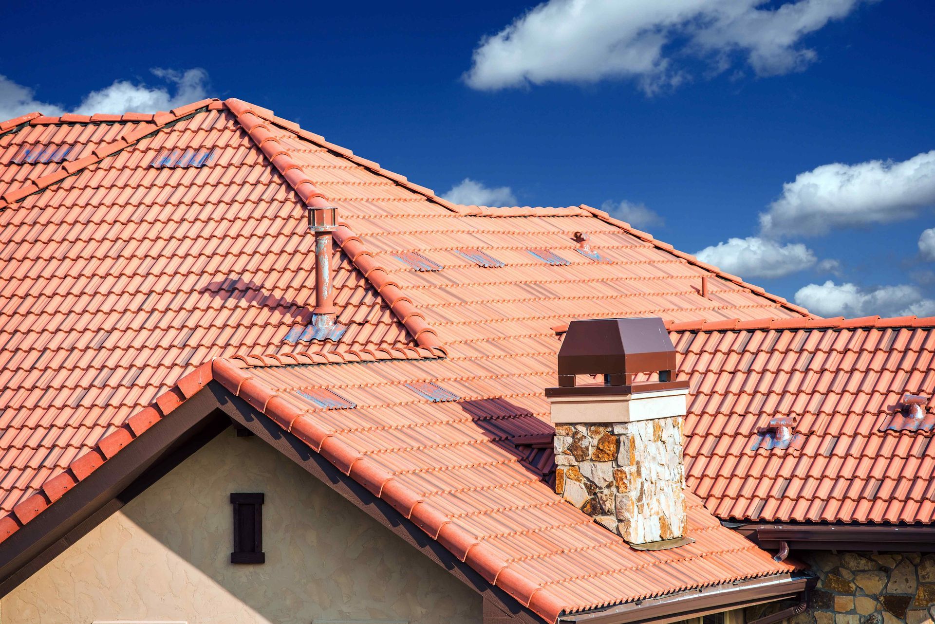 A house with a red tiled roof and a chimney on the roof.