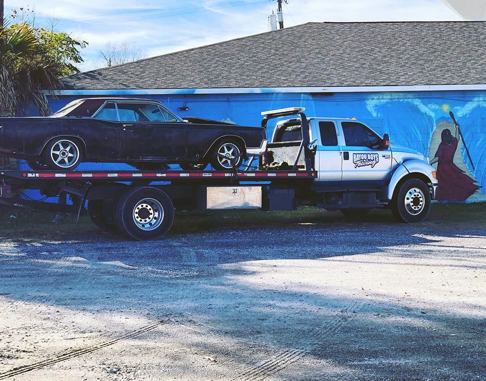 A tow truck is carrying a car on the back of it.