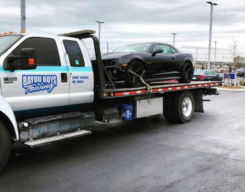 A car is being towed by a tow truck in a parking lot.