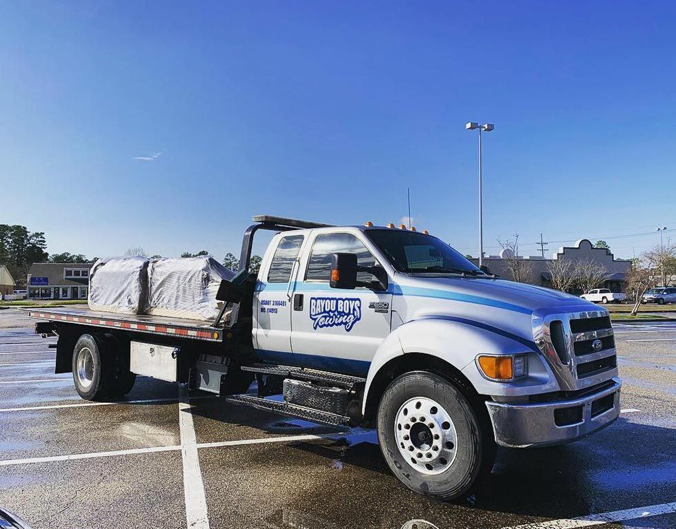 A white tow truck is parked in a parking lot.