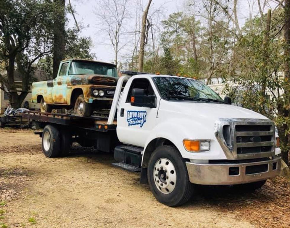 A tow truck is carrying two trucks on the back of it.