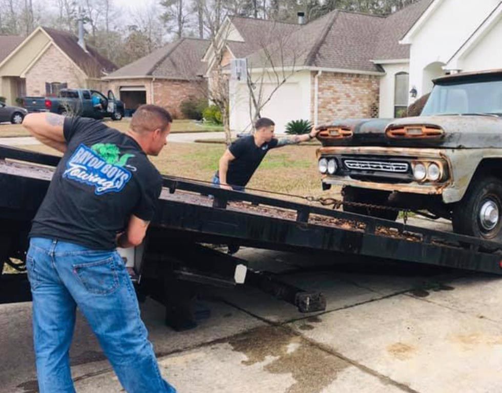 Two men are pushing a truck on a tow truck.