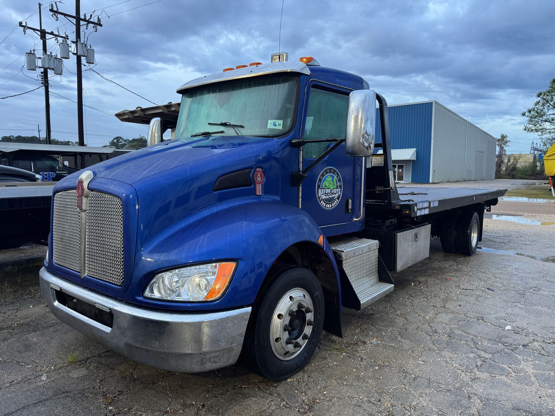 A blue tow truck is parked in a parking lot.