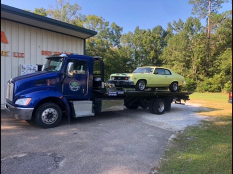 A blue tow truck is carrying a yellow car