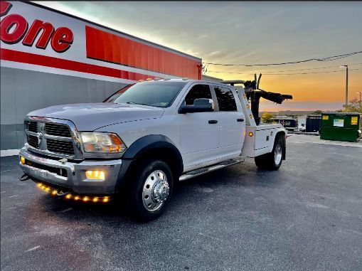 A white tow truck is parked in front of a gas station.