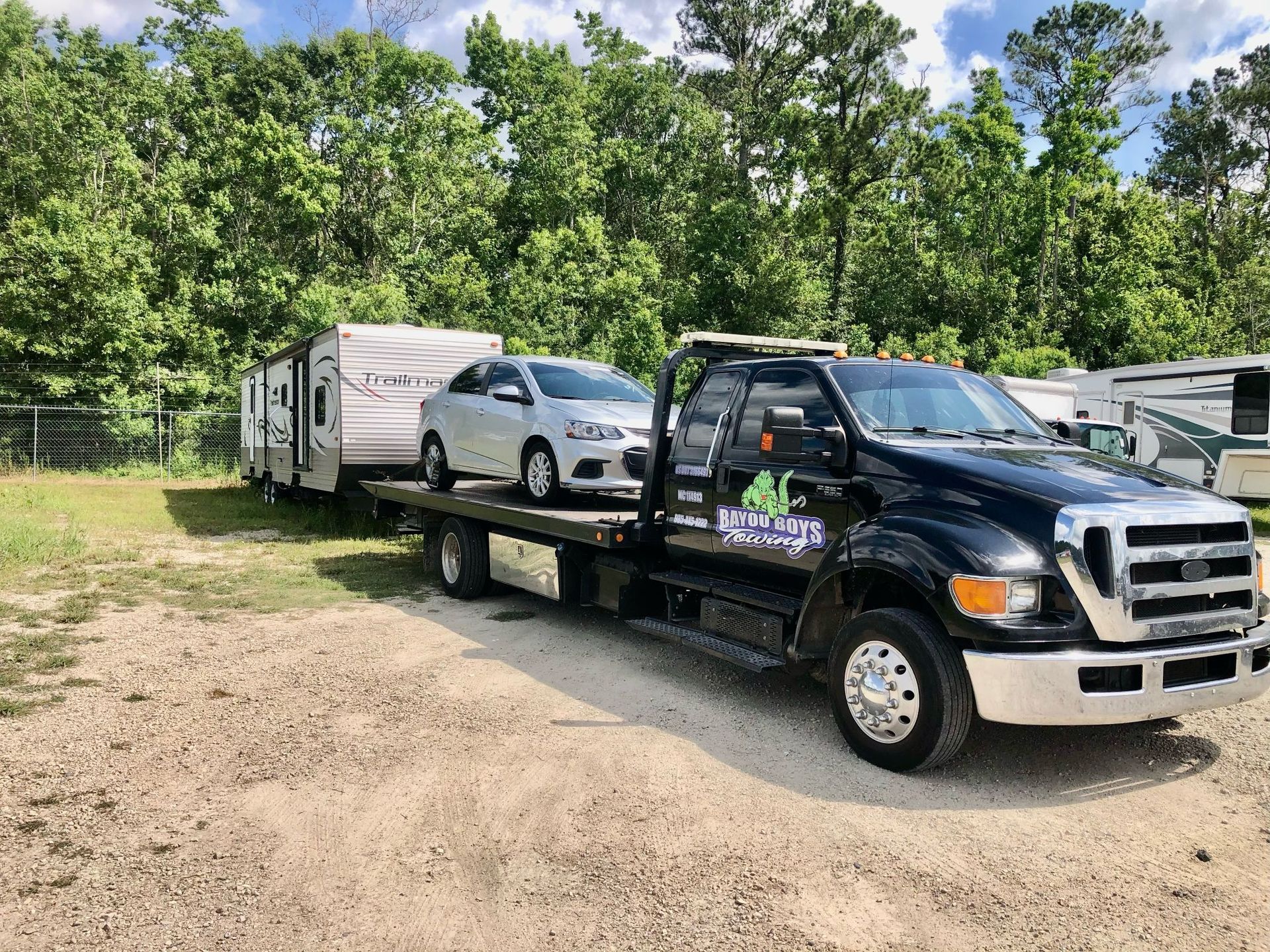 A tow truck is towing a trailer and a car.