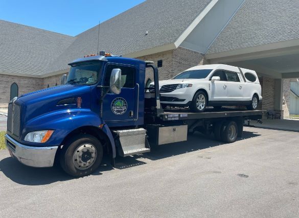 A blue tow truck with a white car on the back of it