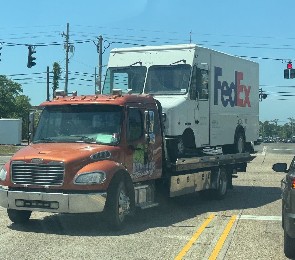 A fedex truck is being towed by a tow truck
