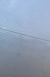 Frau in grünem Hemd wischt Aufzugspiegel mit blauem Tuch ab.