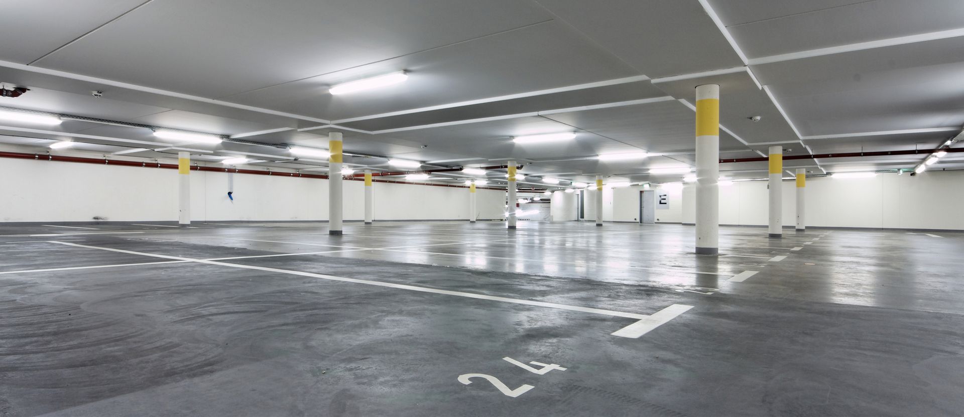 Leere Tiefgarage mit weißen Linien und aufgemalten Zahlen auf dem Boden.
