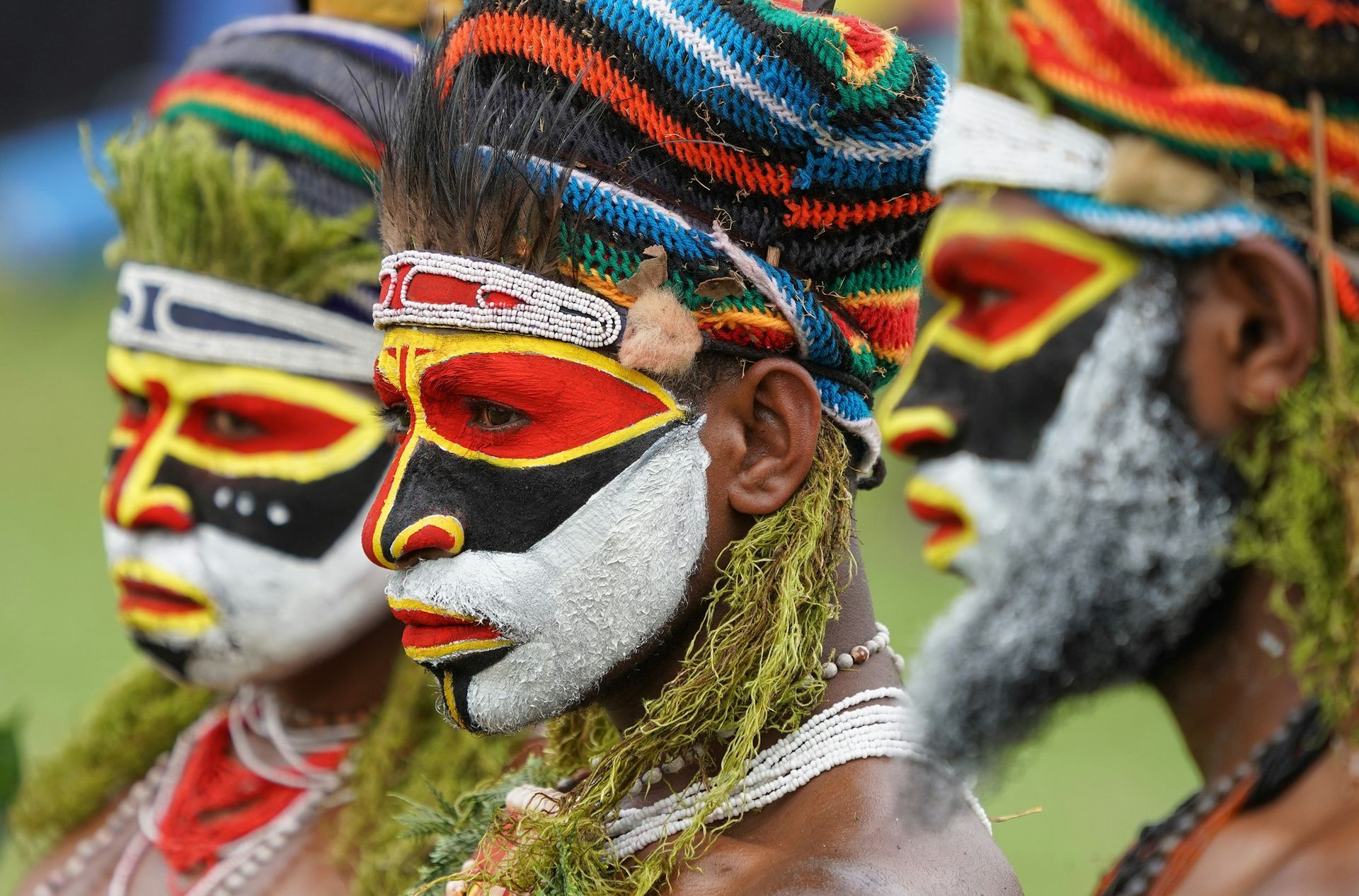 People with vibrant face paint and headdresses at a cultural event.