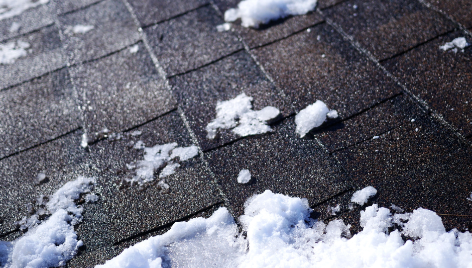 Snow scattered on a dark shingled roof