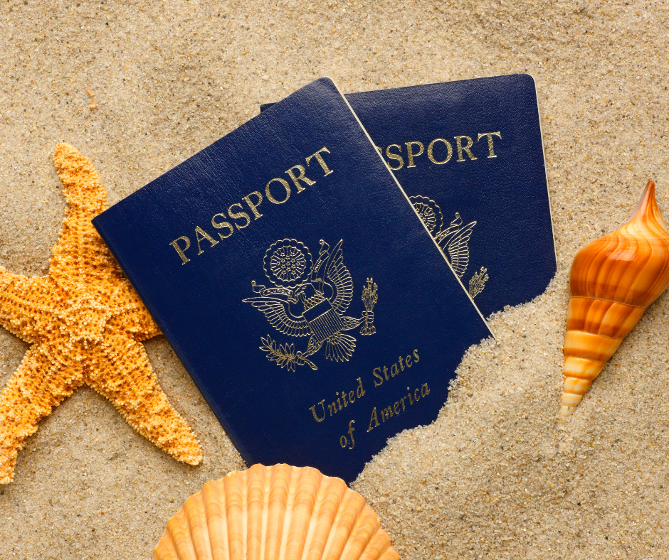 Two blue United States passports placed on sand with a starfish and seashells.