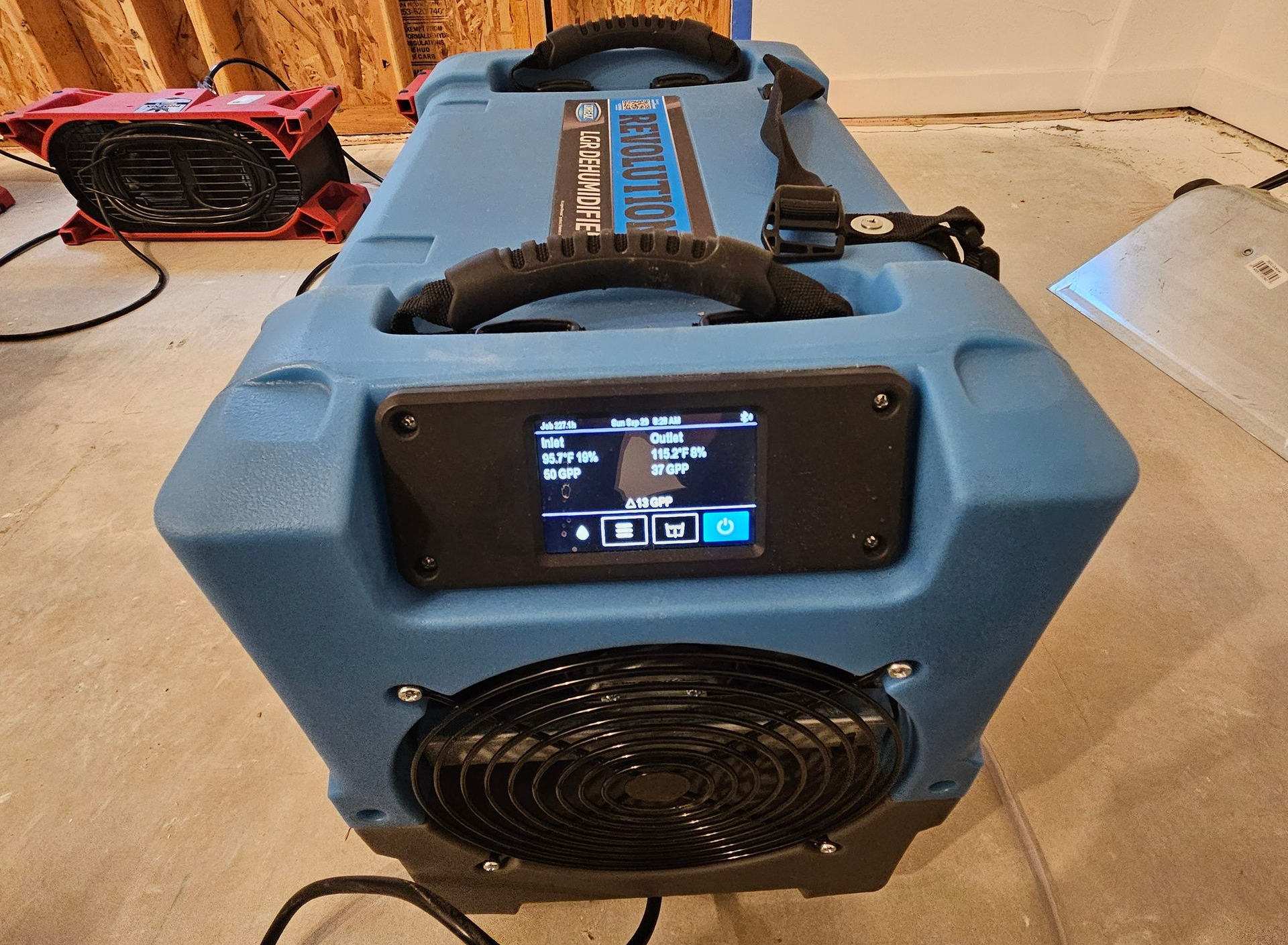 Blue portable air mover blower with a digital display and front fan, sitting on a floor indoors