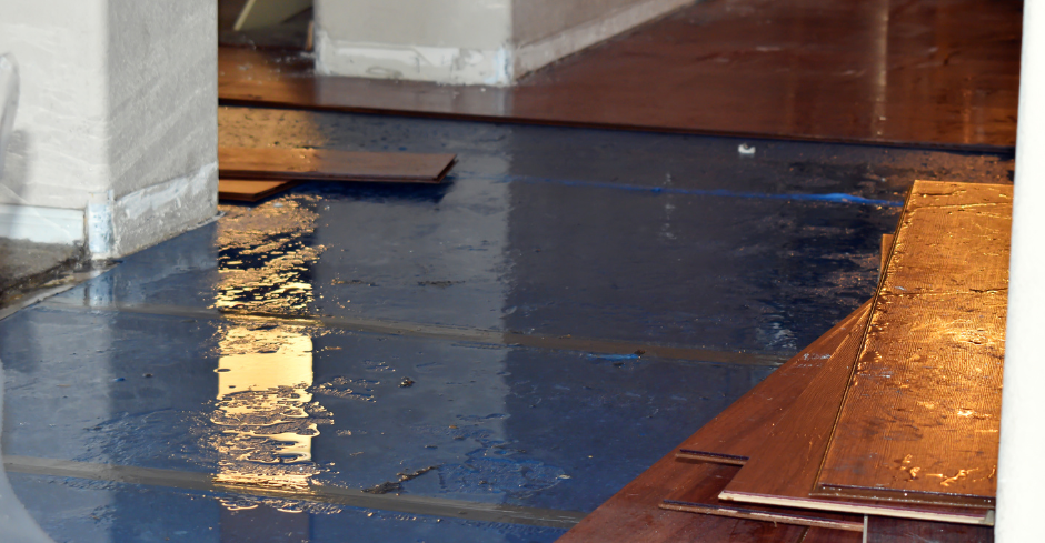 Water-damaged floor with wood planks floating in the standing water; interior shot.