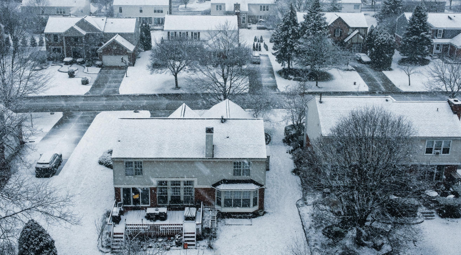 Snowy suburban neighborhood; houses and streets covered in snow.