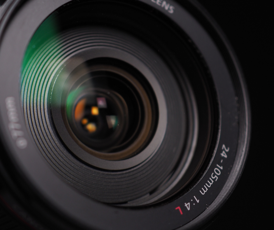 Close-up of a black camera lens with reflective glass and white focal-length markings