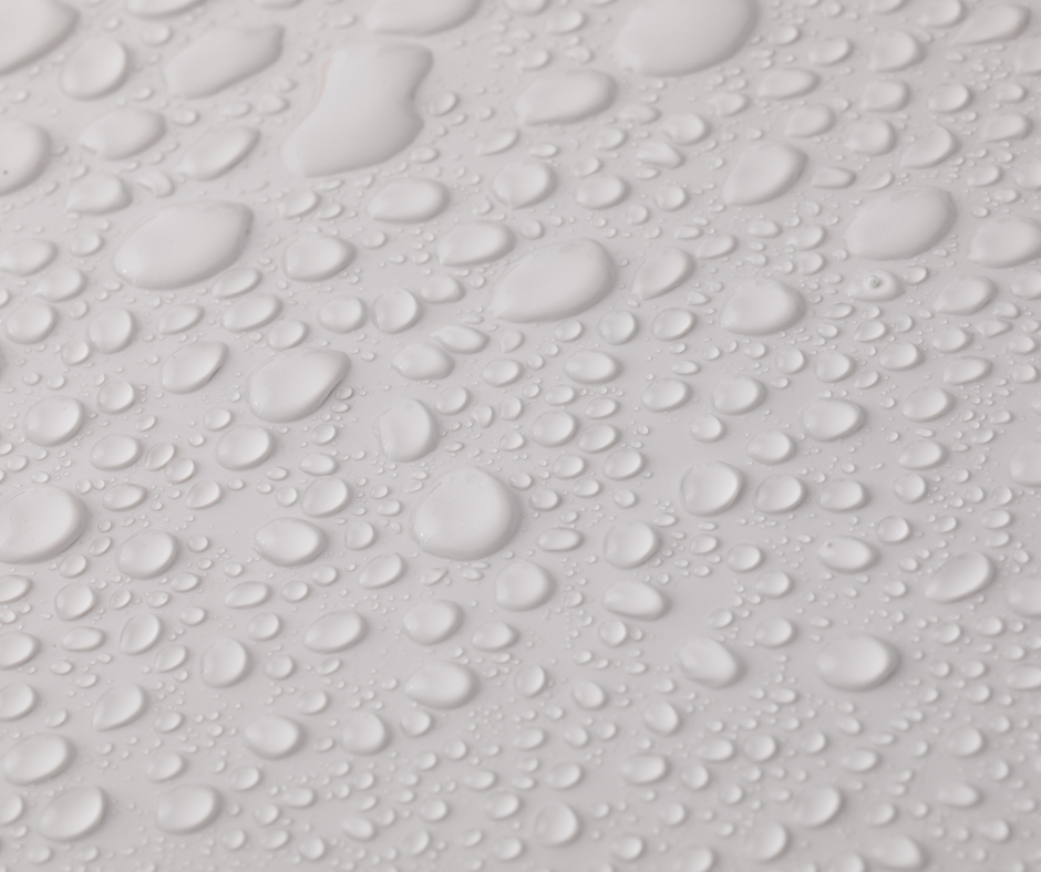 Close-up of clear water droplets on a light gray surface