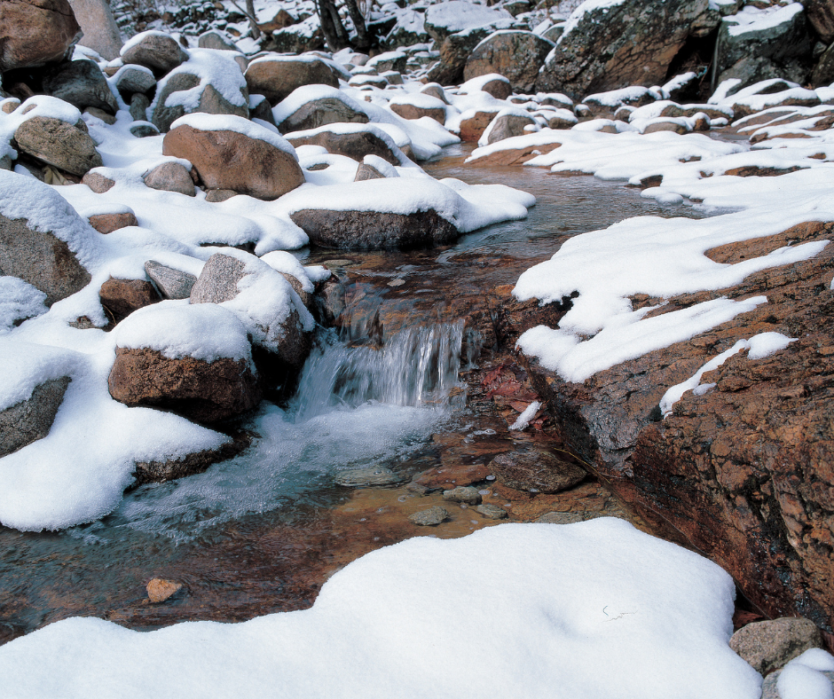 Snowy stream flowing over rocks in a winter landscape.