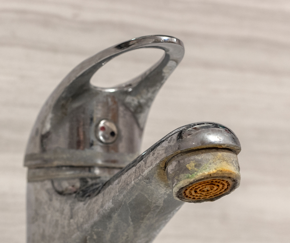 Close-up of a chrome faucet with significant mineral buildup around the spout.