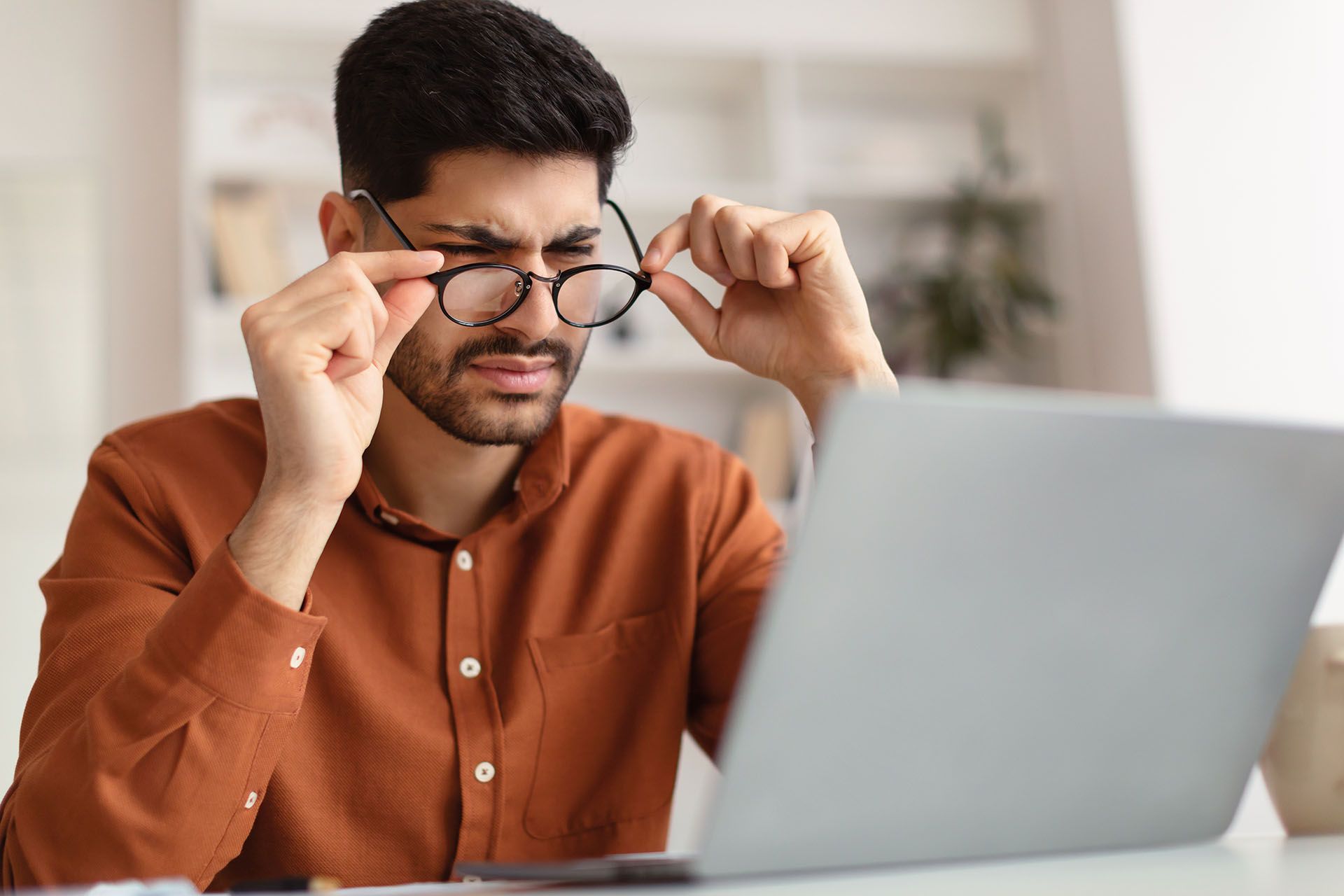 man having trouble reading on a laptop