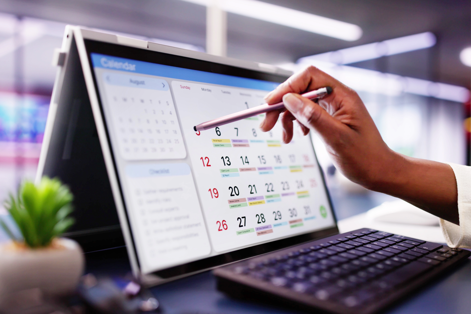 Person using a stylus on a laptop screen displaying a calendar.