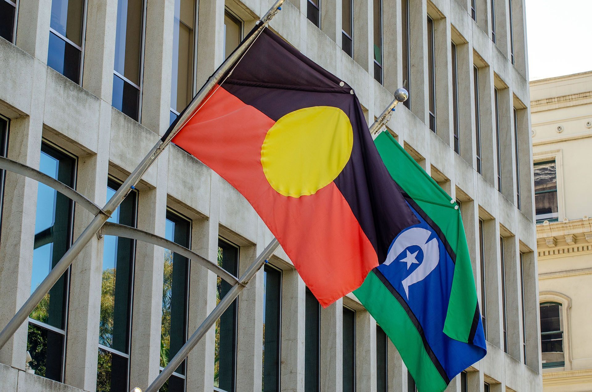 Two flags are flying in front of a building