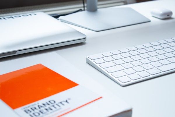 A book titled brand identity sits on a desk next to a keyboard