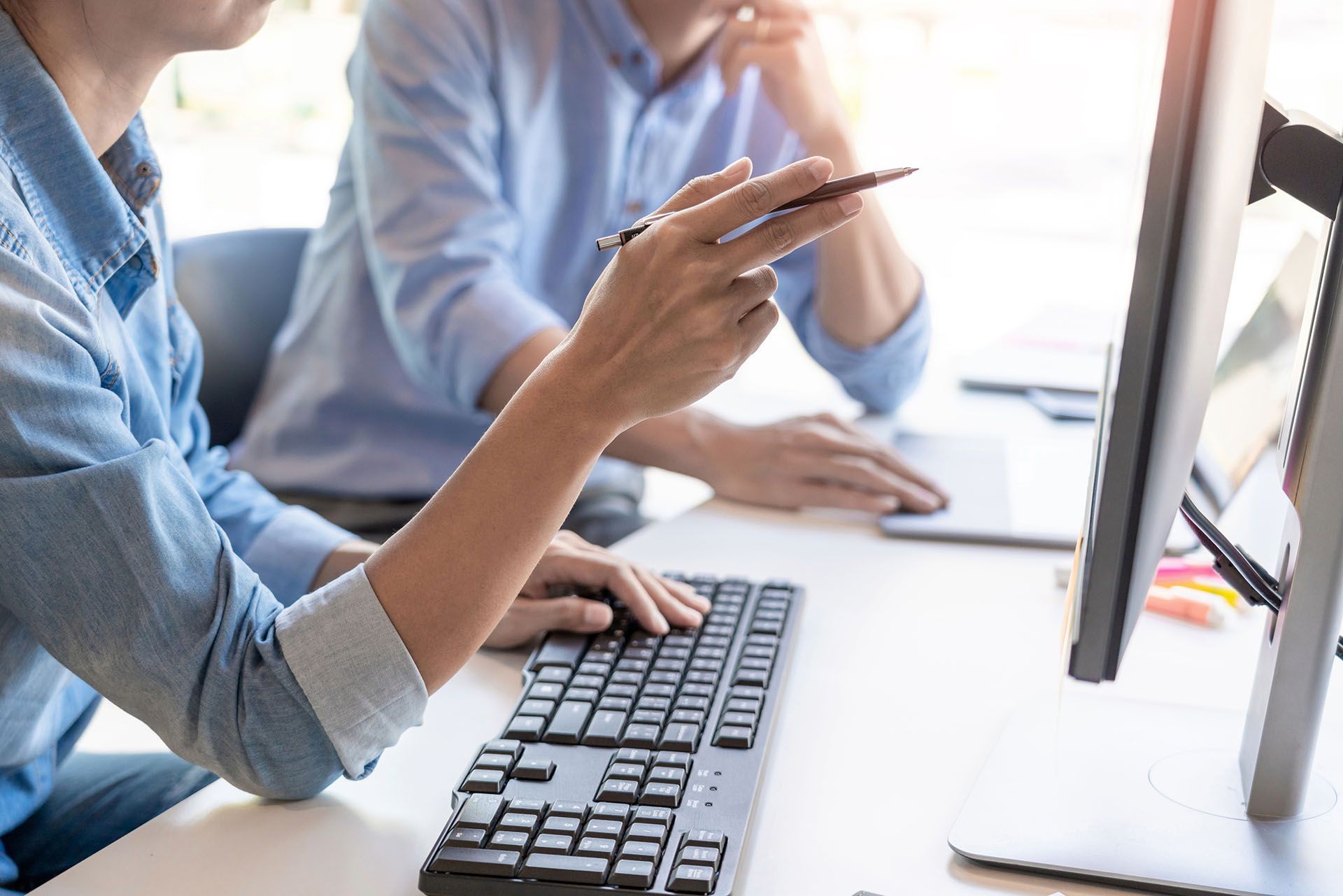 Two men are sitting at a desk working on a computer.