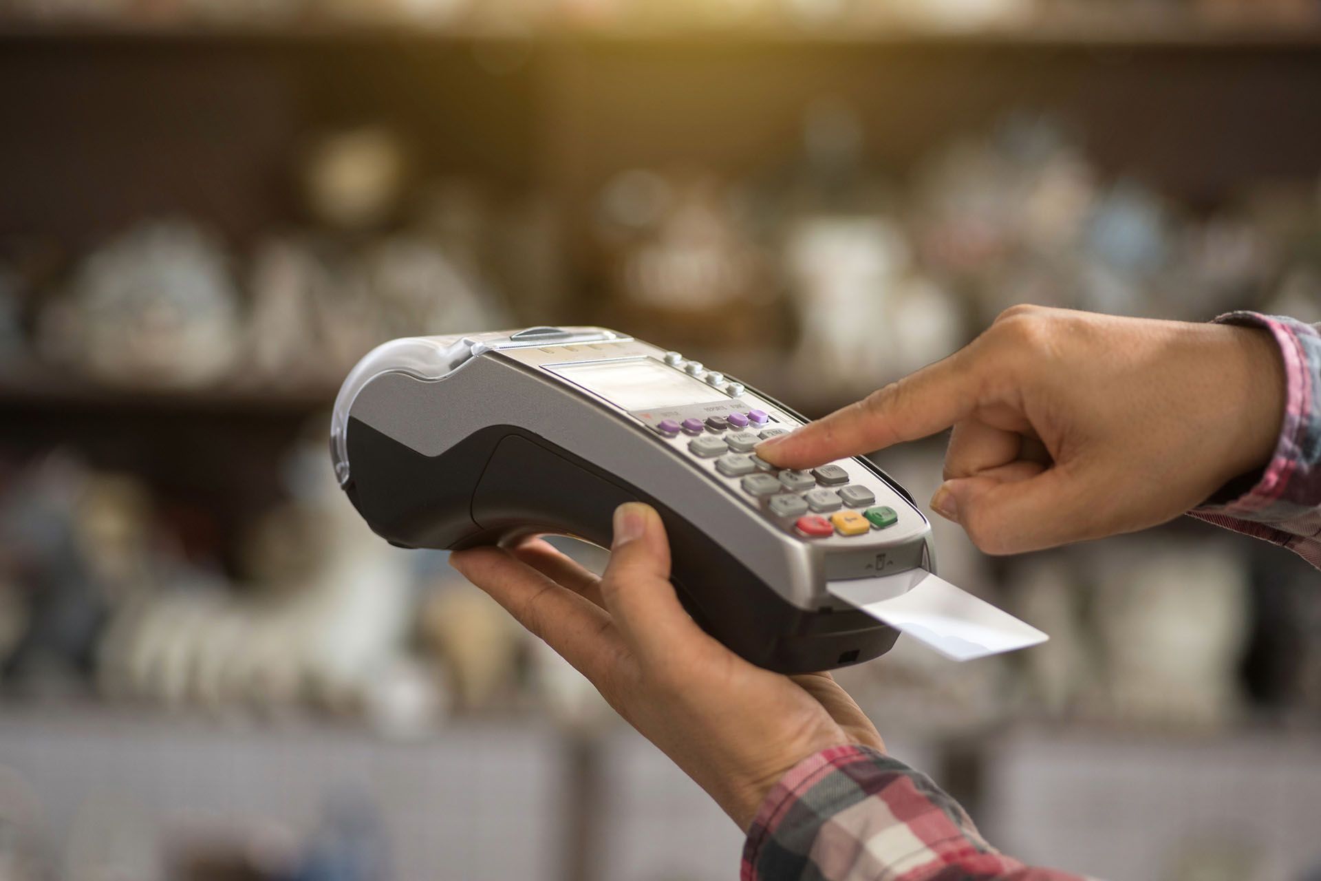 Person entering a PIN on a credit card reader in a store.