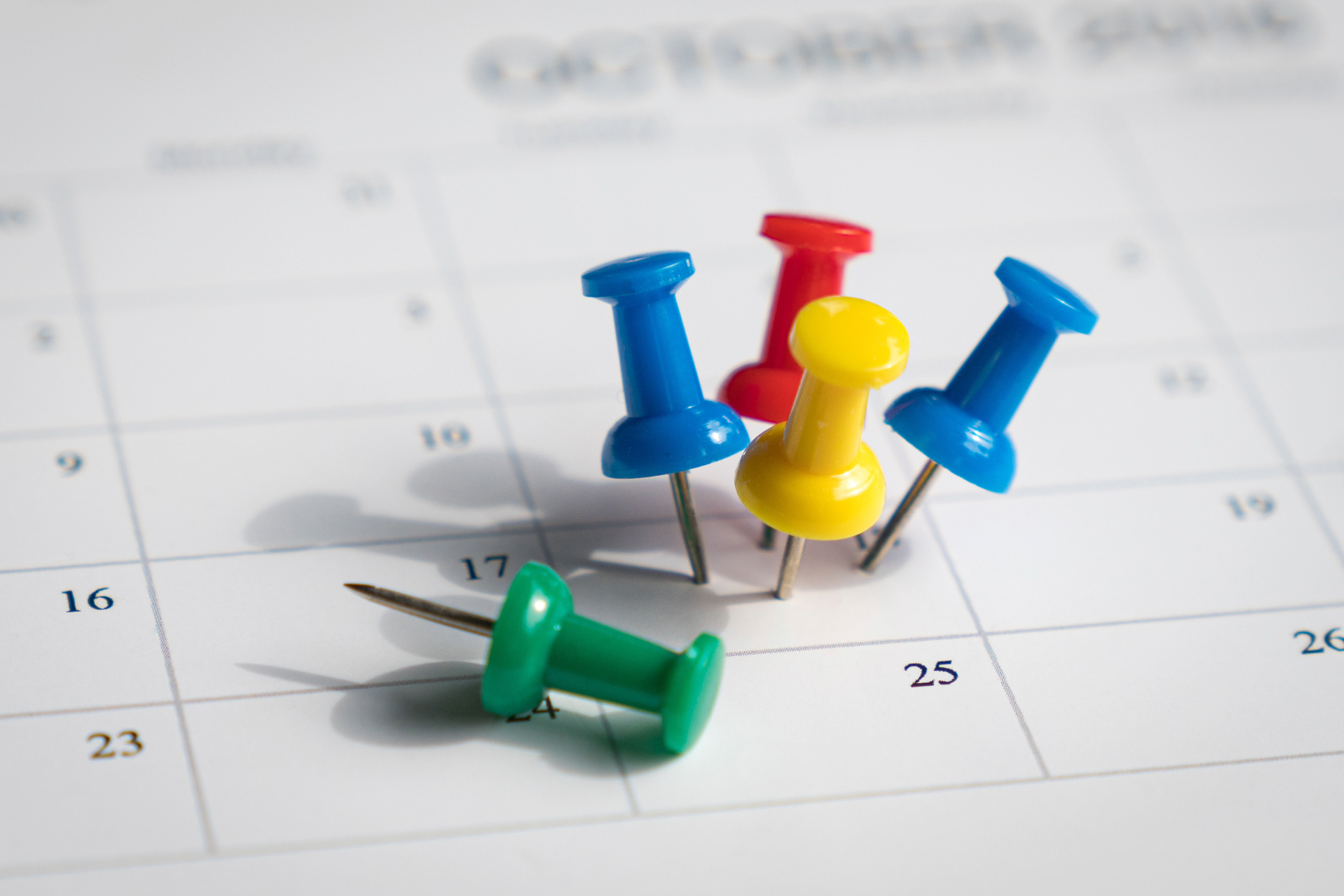 Colorful push pins on a calendar highlighting several dates.