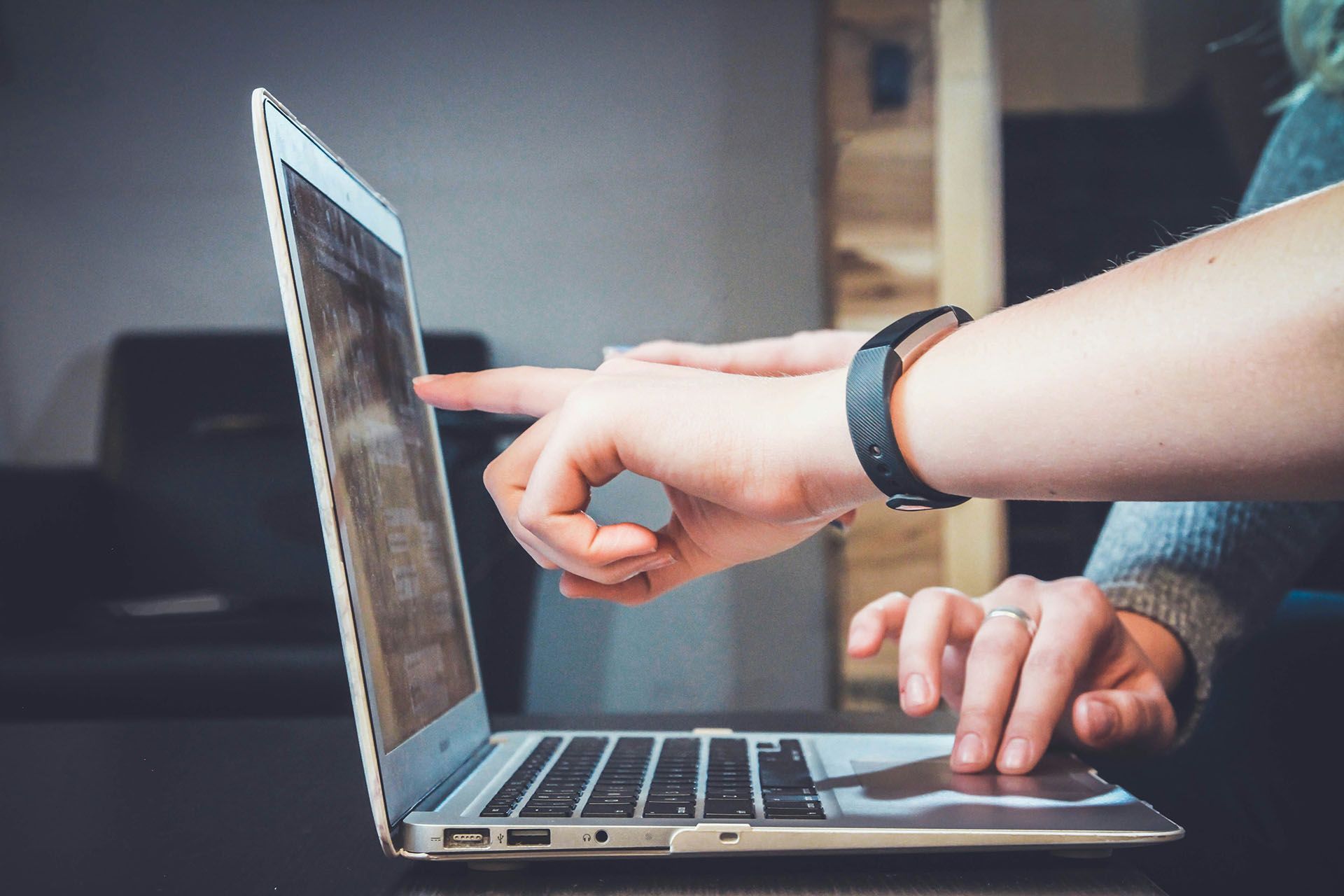 Two people are pointing at a laptop screen.