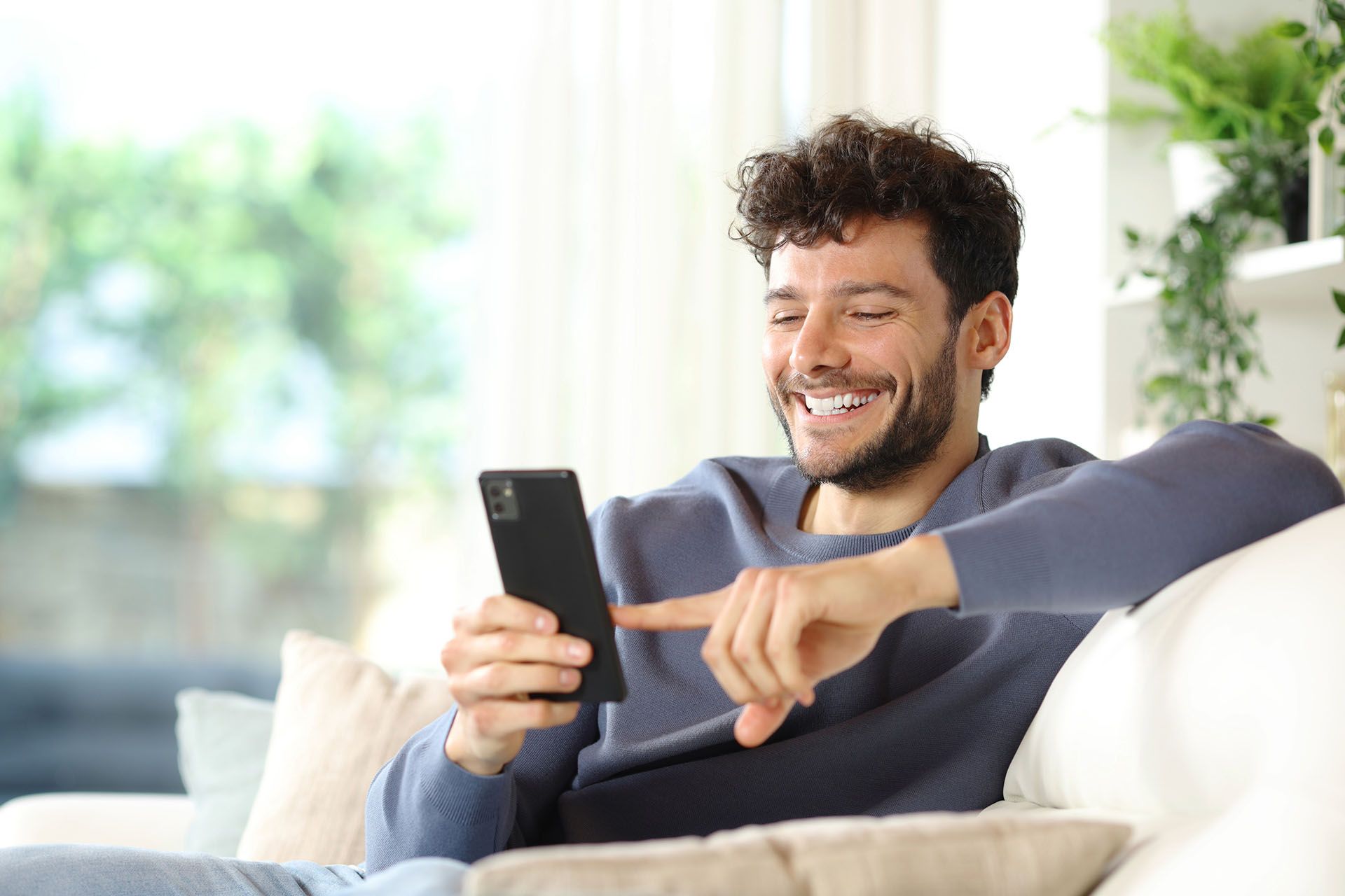 A man is sitting on a couch using a cell phone.