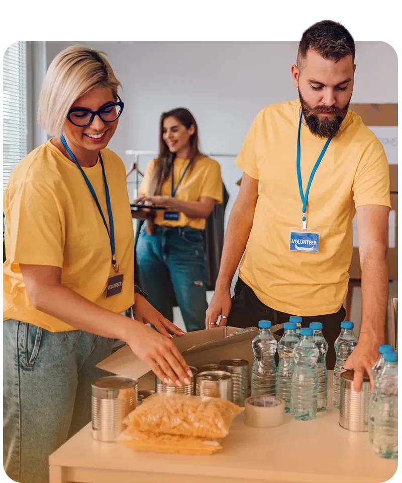 A group of volunteers in yellow shirts are standing around a table.