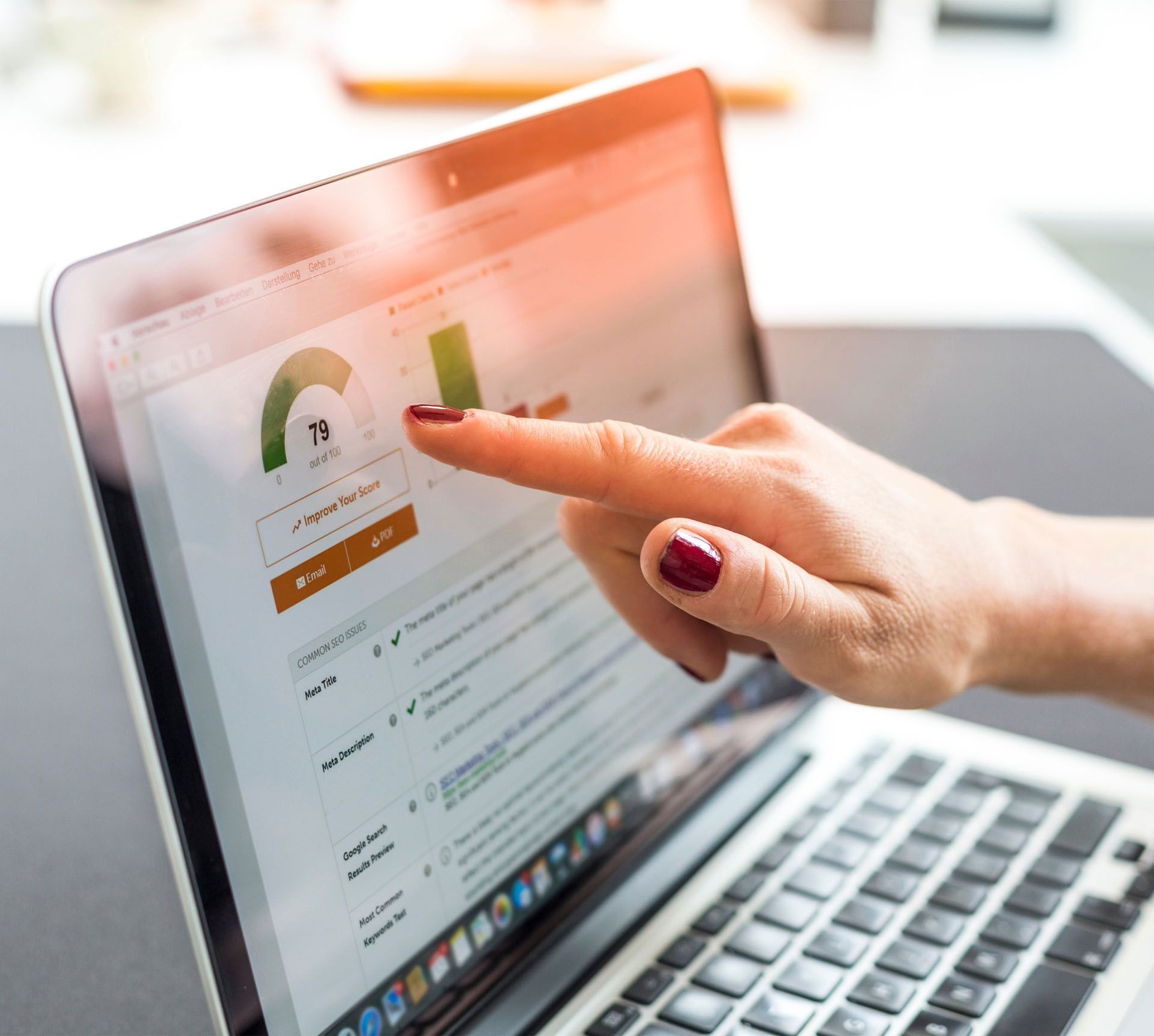 A woman is pointing at a graph on a laptop computer.