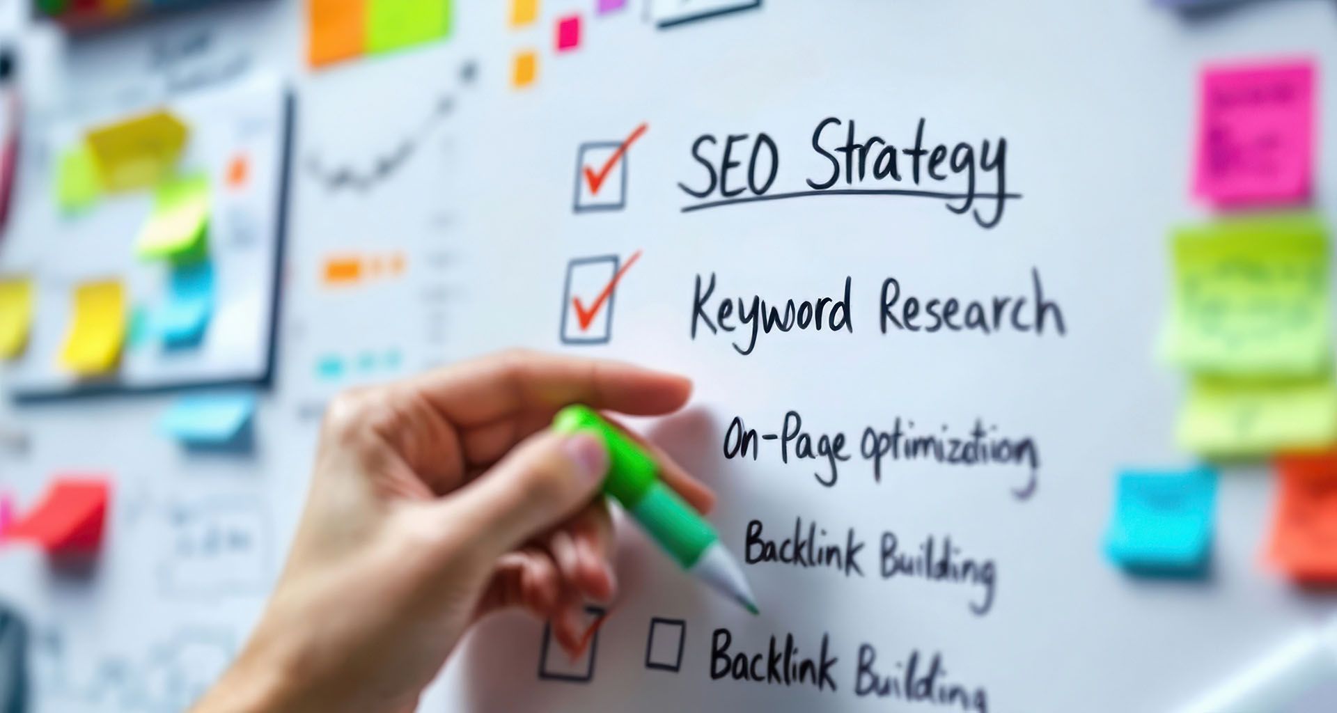 Hand holding a green pen marking a checklist about SEO strategy